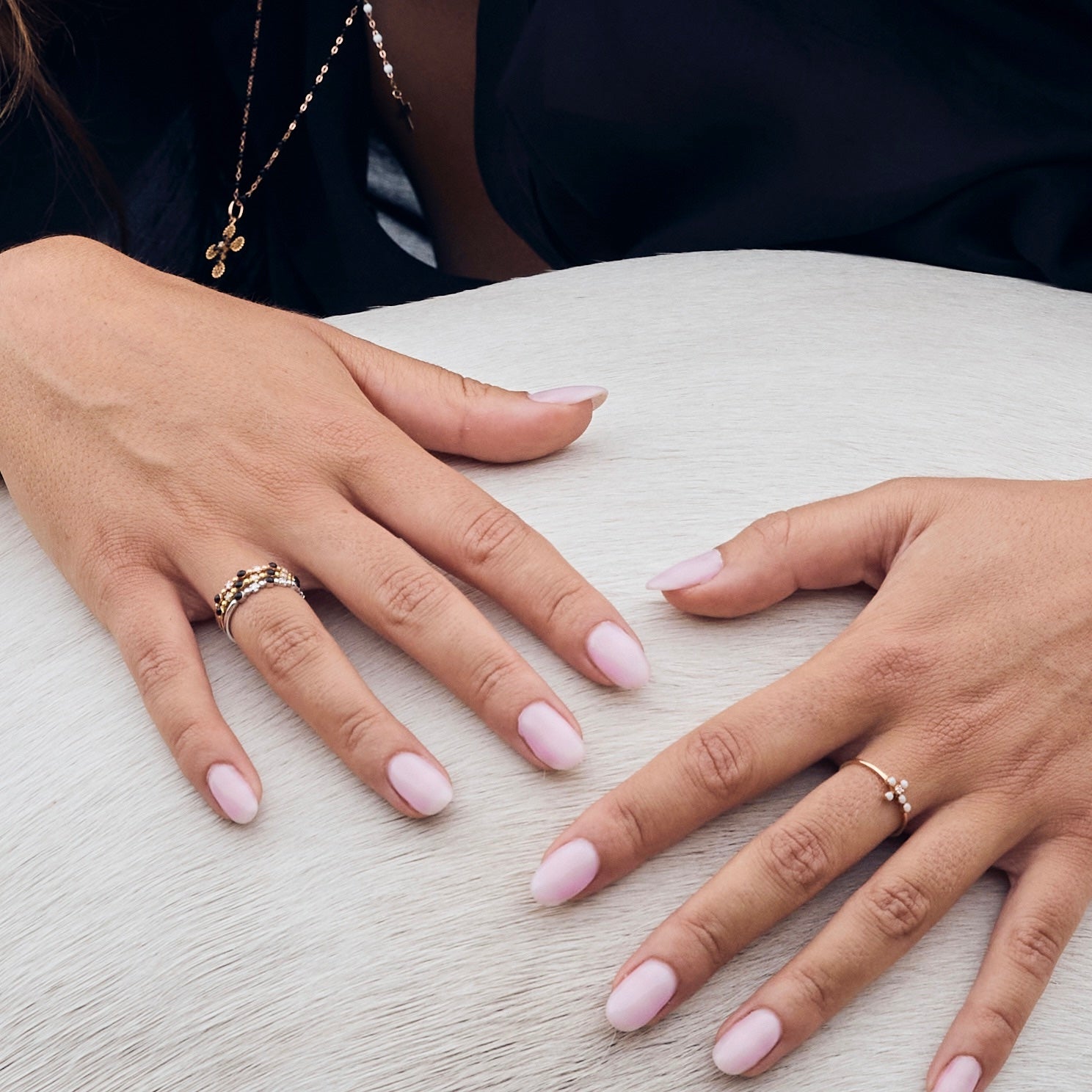 Photo des mains d’une femme posées sur un cheval, portant plusieurs bagues Gigi Clozeau noires et blanches.