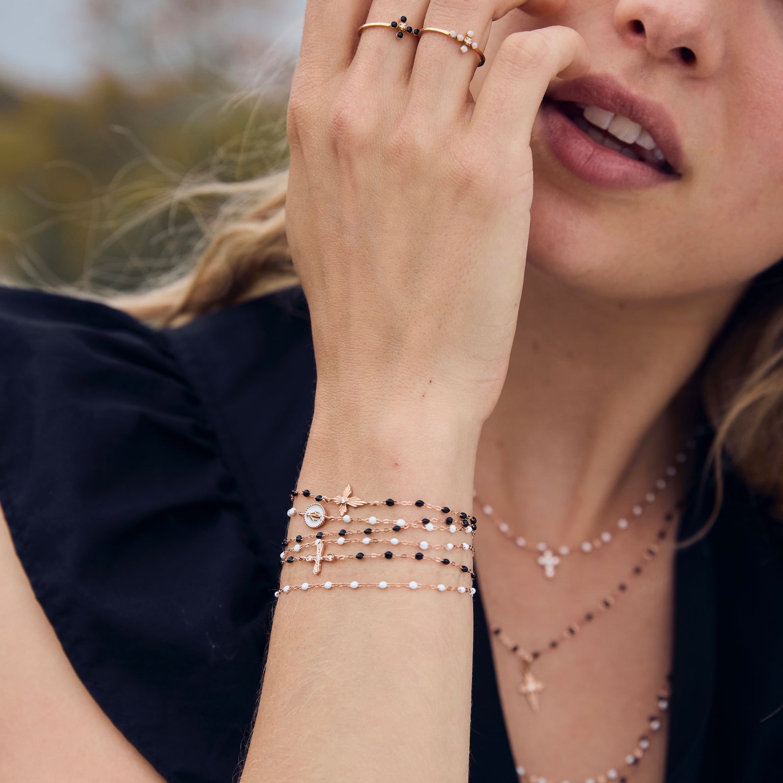 Photo du poignet d’une femme portant plusieurs bracelets Gigi Clozeau noirs et blancs.