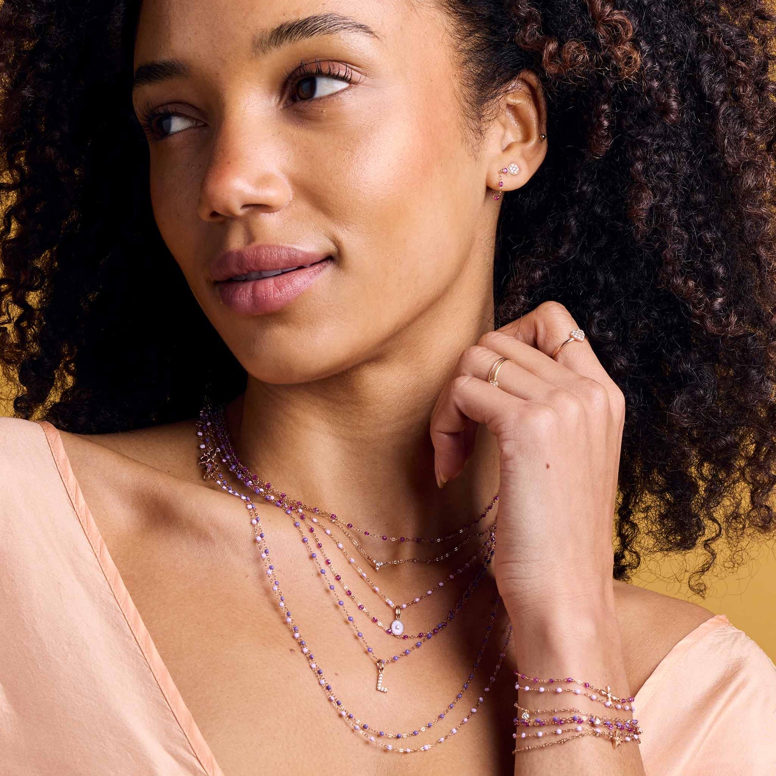 Photo du visage d'une femme portant des boucles d'oreilles, des colliers et des bracelets Gigi Clozeau de couleur galaxy. 