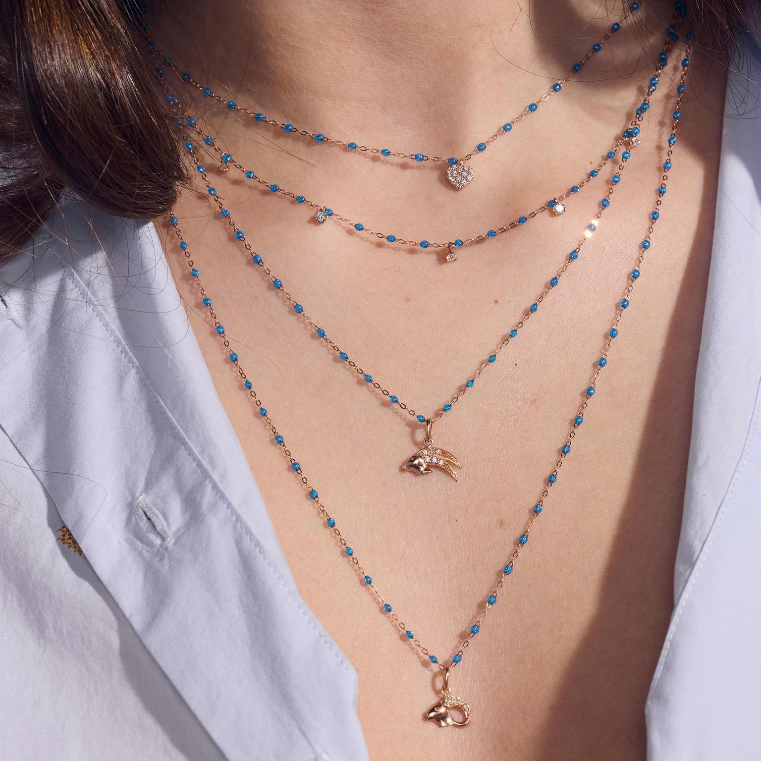 Photo du cou d’une femme portant une sélection de colliers Gigi Clozeau de la nouvelle couleur azur.