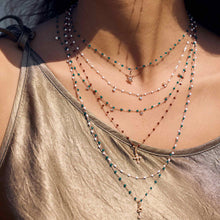 Photo du cou d’une femme portant plusieurs colliers de différentes couleurs et modèles de Gigi Clozeau.