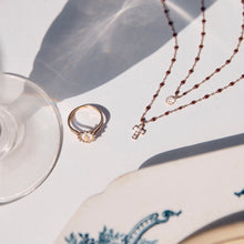 Photo d'une bague et de deux colliers Gigi Clozeau posés sur une table.